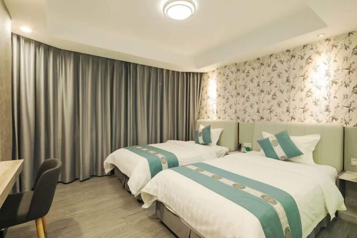 A hotel room with two beds, a desk, and a chair.