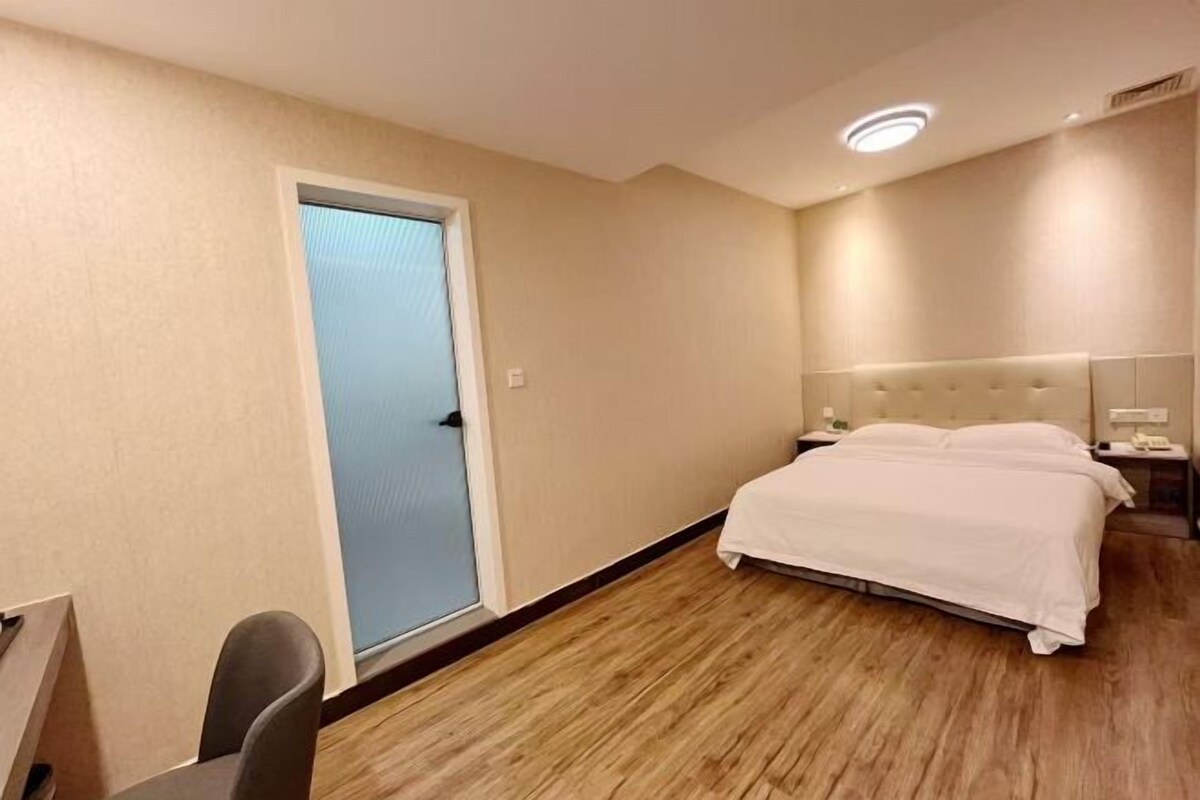 Una habitación de hotel con cama, mesita de noche y una puerta.