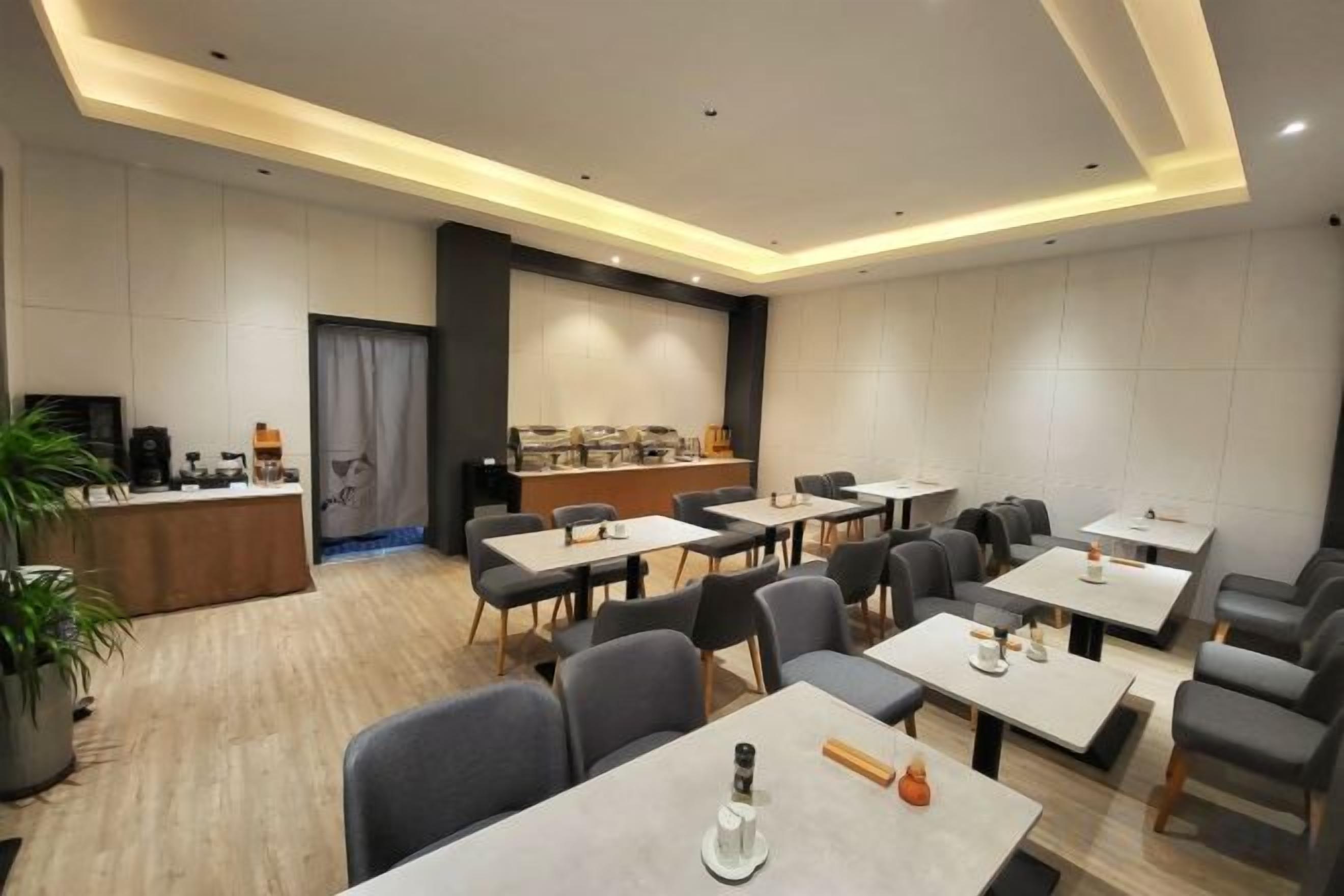A modern hotel conference room with tables, chairs, a bar, and a projection screen.