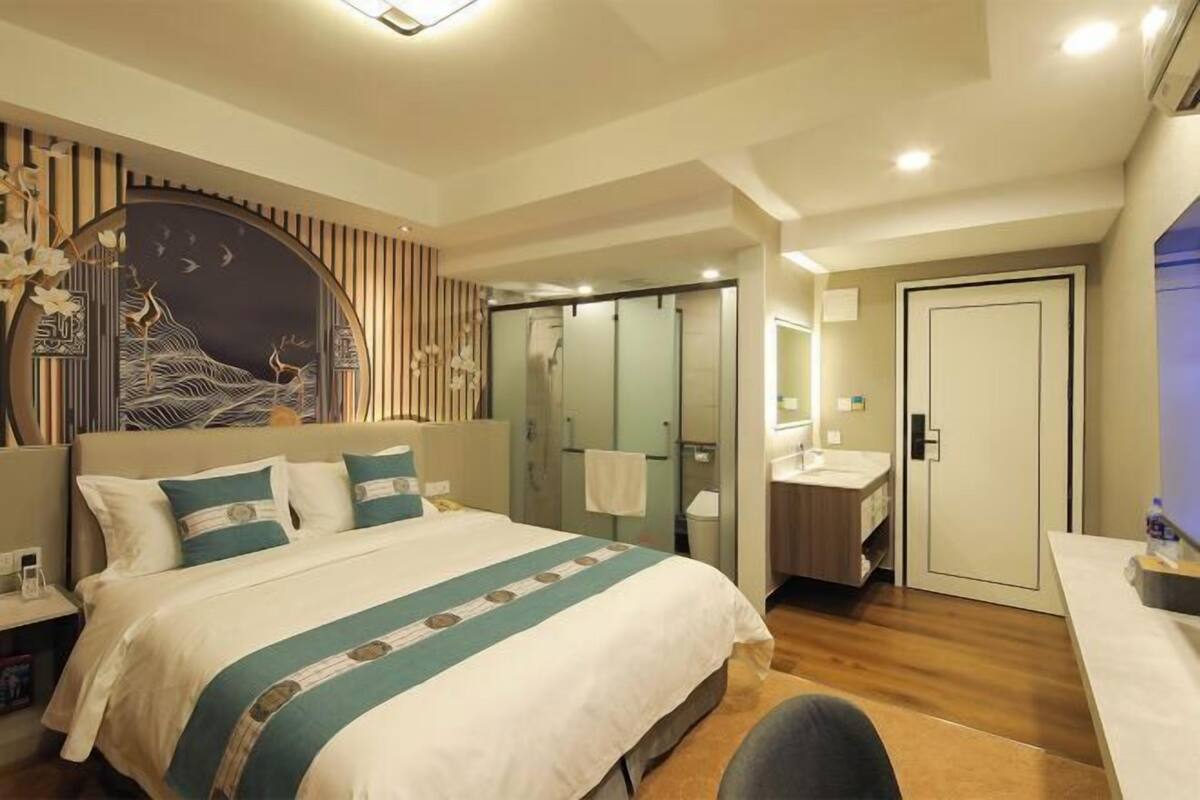 Une chambre d’hôtel moderne avec un grand lit, une coiffeuse et un dressing.