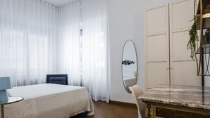 Ein Hotelzimmer mit Bett, Schreibtisch, Stuhl, Spiegel und Tür.