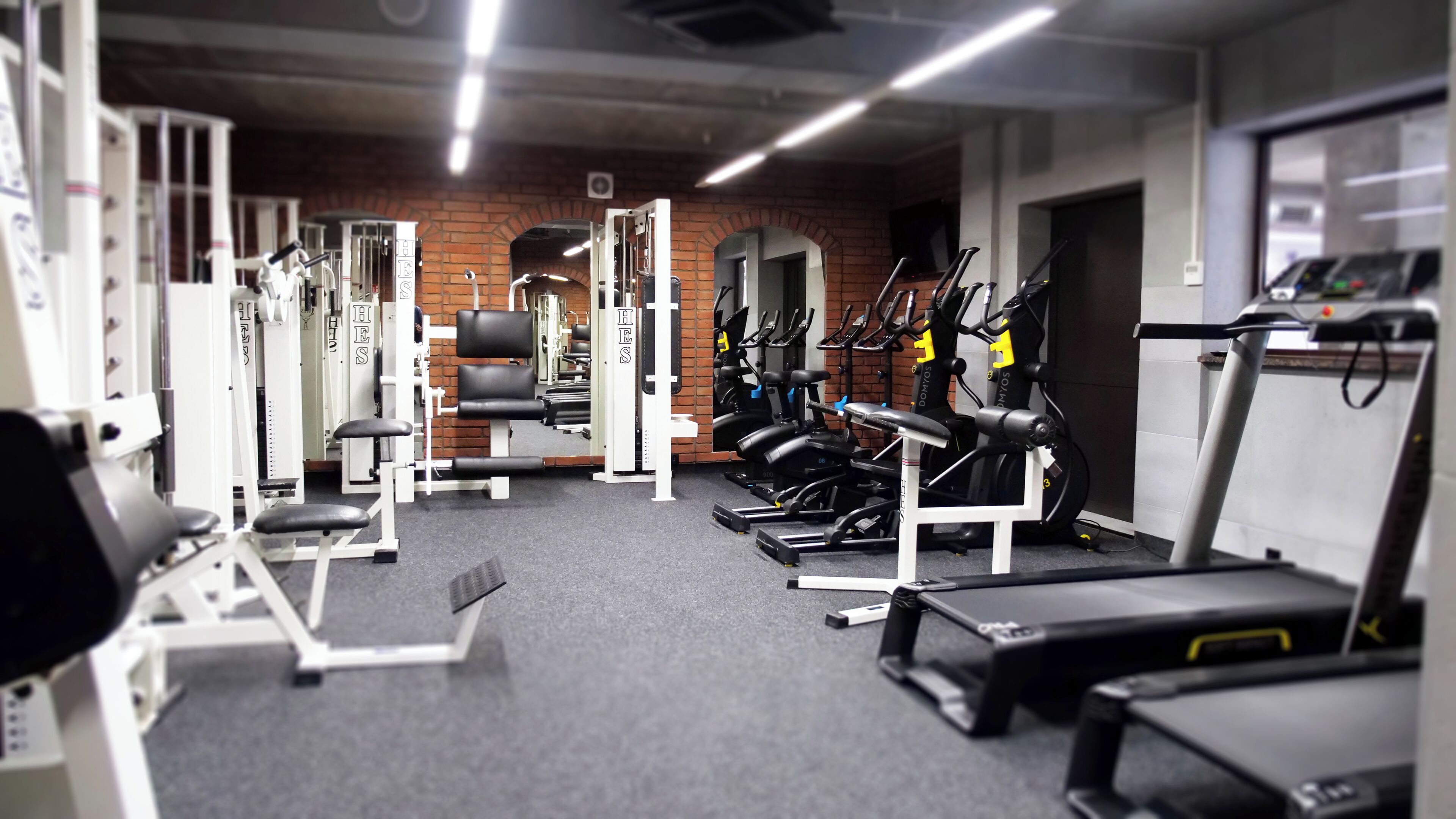 Un gimnàs amb diferents equips d'exercici, incloent cintes de córrer i aparells de musculació.