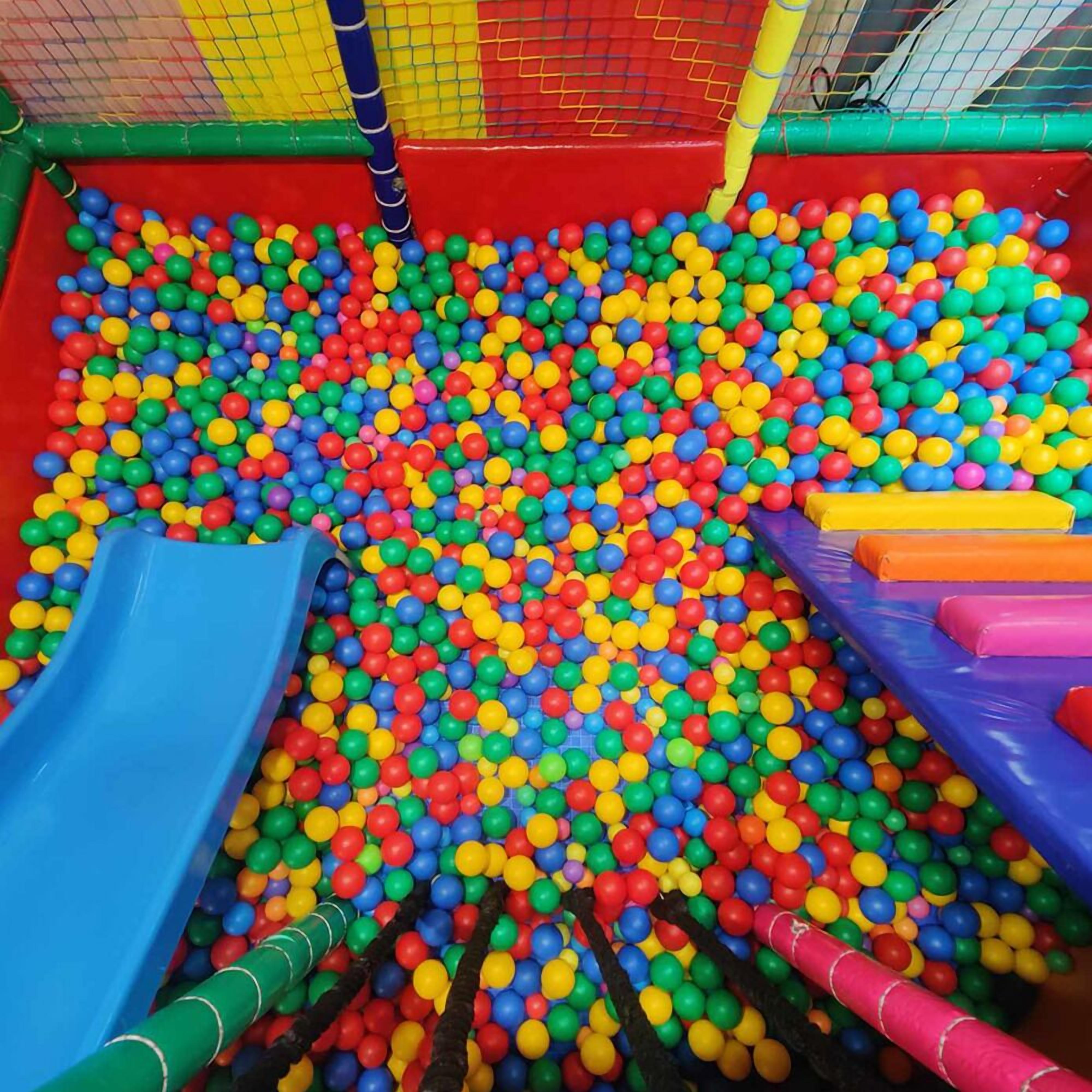 A colorful indoor play area with a ball pit, slides, and soft play structures.