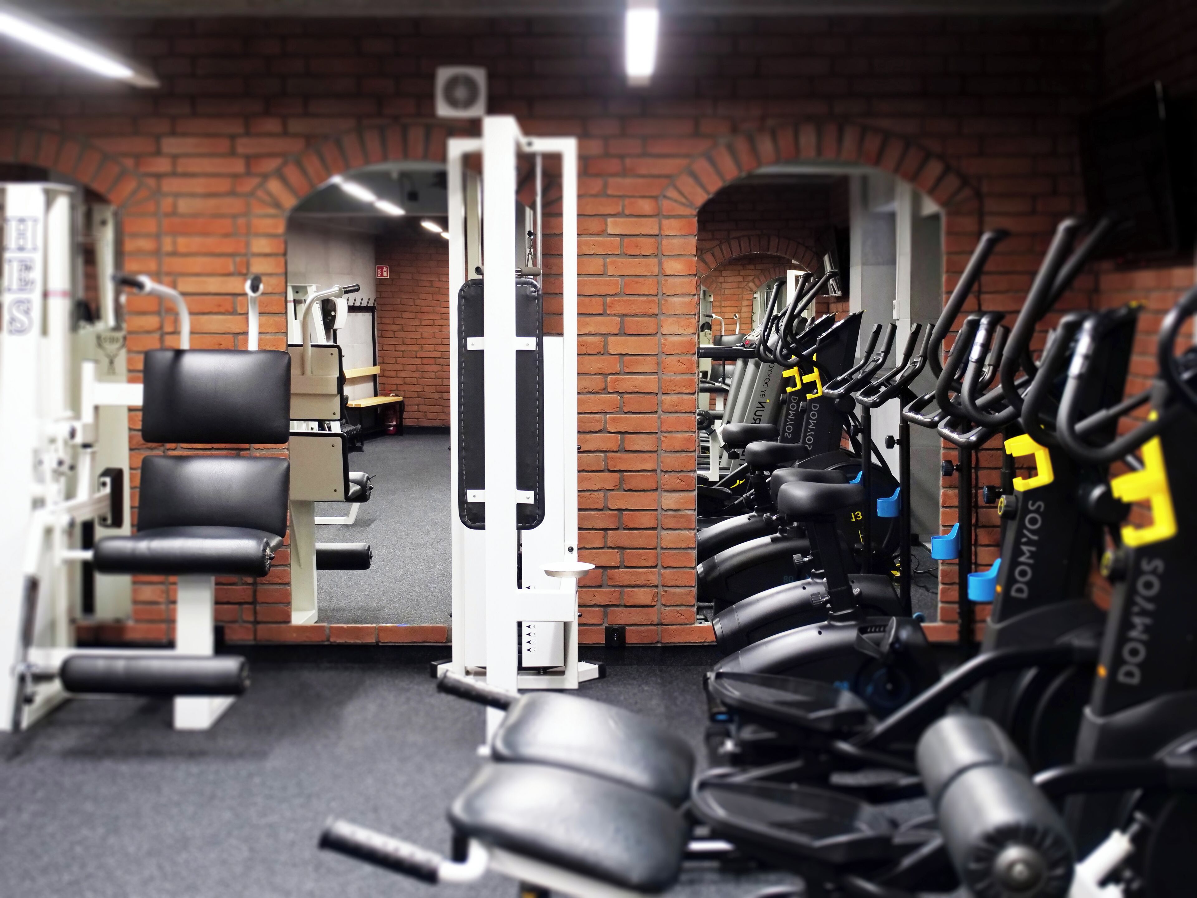 A gym with exercise equipment, brick walls, and a mirrored wall.