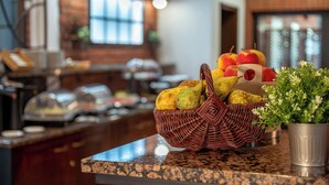 A buffet area with a wicker basket containing fruits and a potted plant.