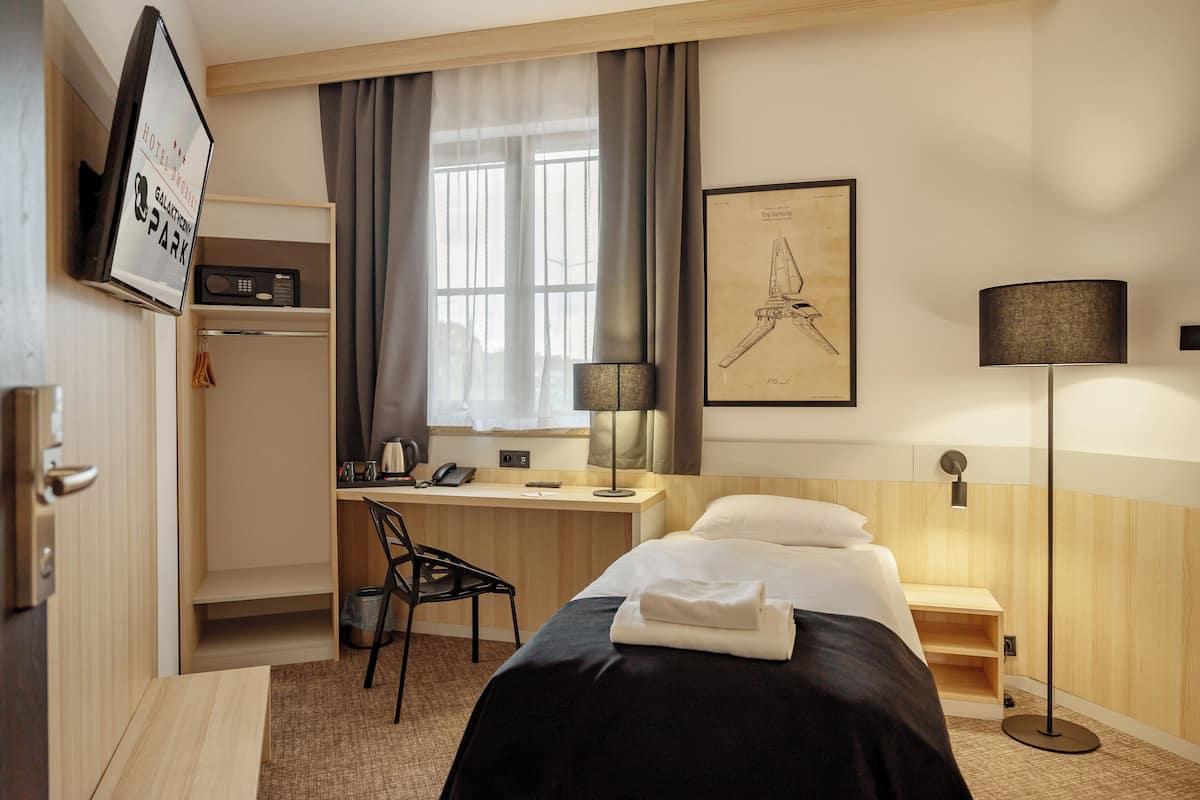 Une chambre d’hôtel avec un lit, un bureau, une chaise et une œuvre d’art encadrée au mur.