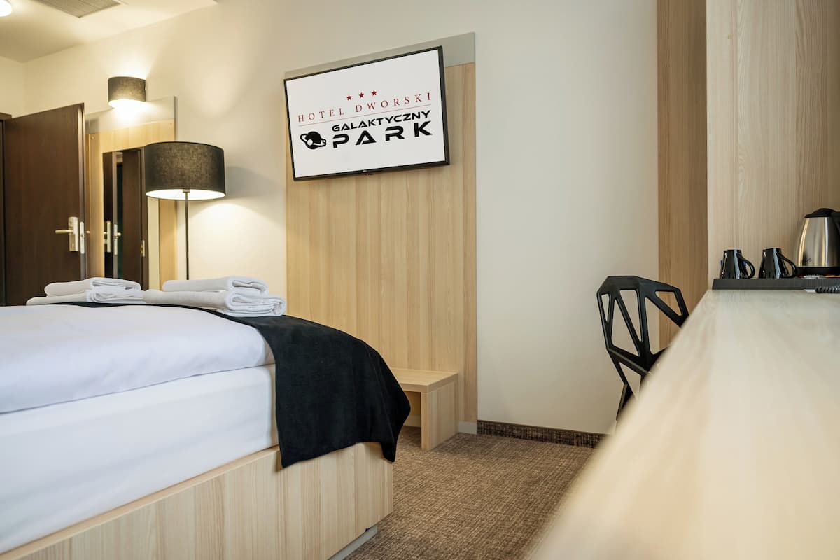 Une chambre d’hôtel équipée d’un lit, d’un bureau, d’une chaise, d’une lampe et d’une pancarte indiquant que l’hôtel se trouve dans le parc Galaxy.