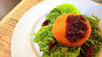 A plate with a salad and a breaded item on top, placed on a table with a menu in the background.