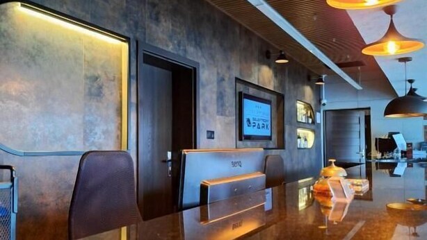 A modern reception area with a long counter, seating, and a television screen.