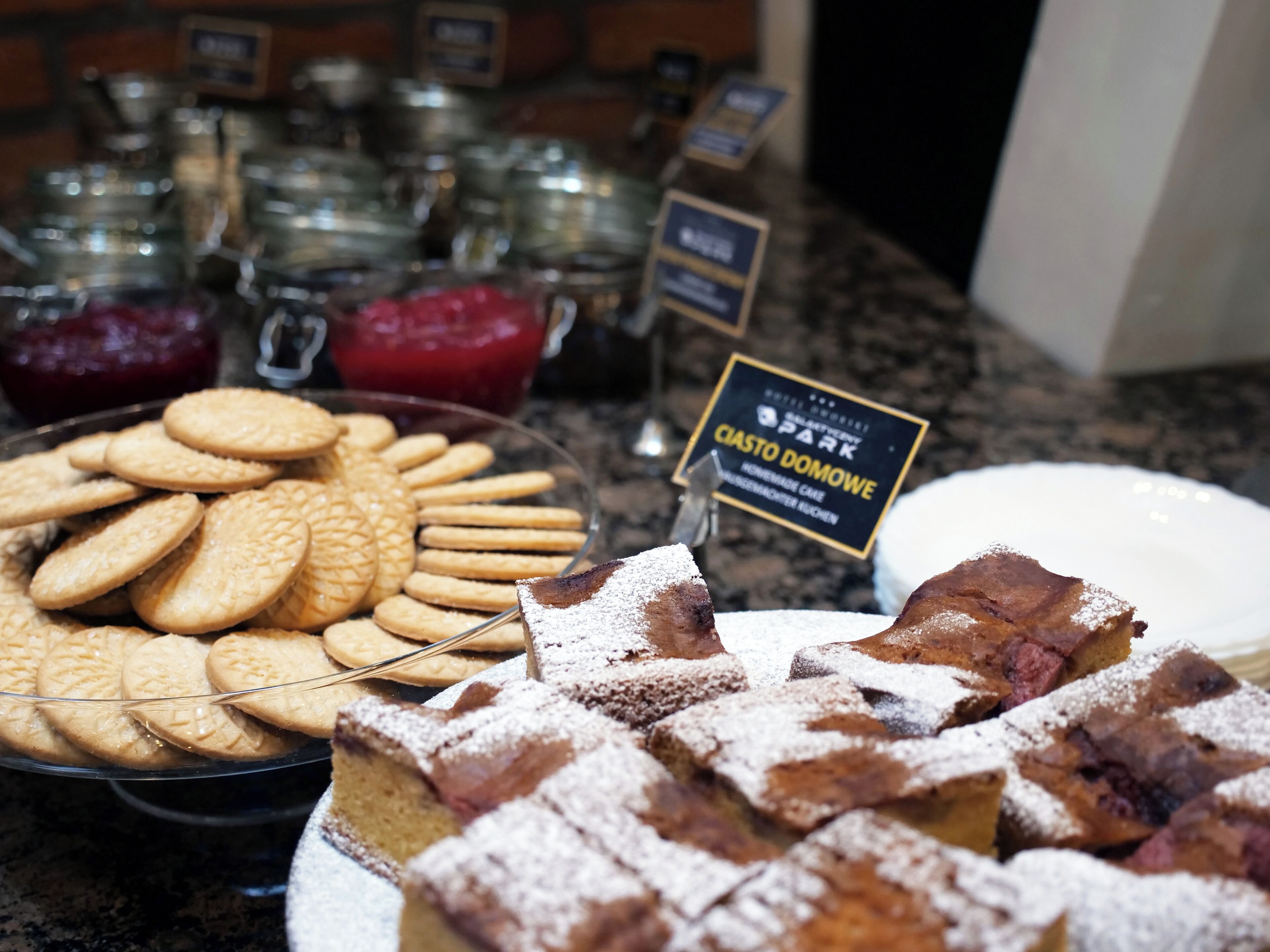A buffet with various baked goods including cookies and a cake with powdered sugar.