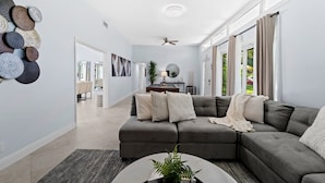 A modern living room with a sectional sofa, a coffee table, and a decorative wall. - 4BR Intracoastal Retreat With Pool, Games & More! (West Palm Beach)
