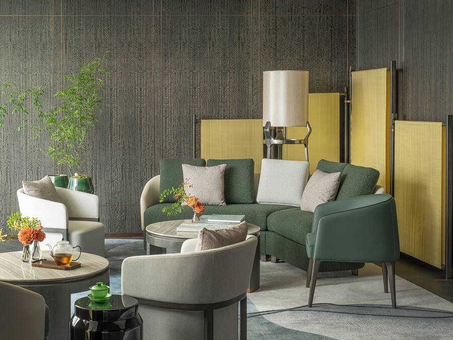 A modern living room with a sofa, armchairs, a coffee table, and a lamp.