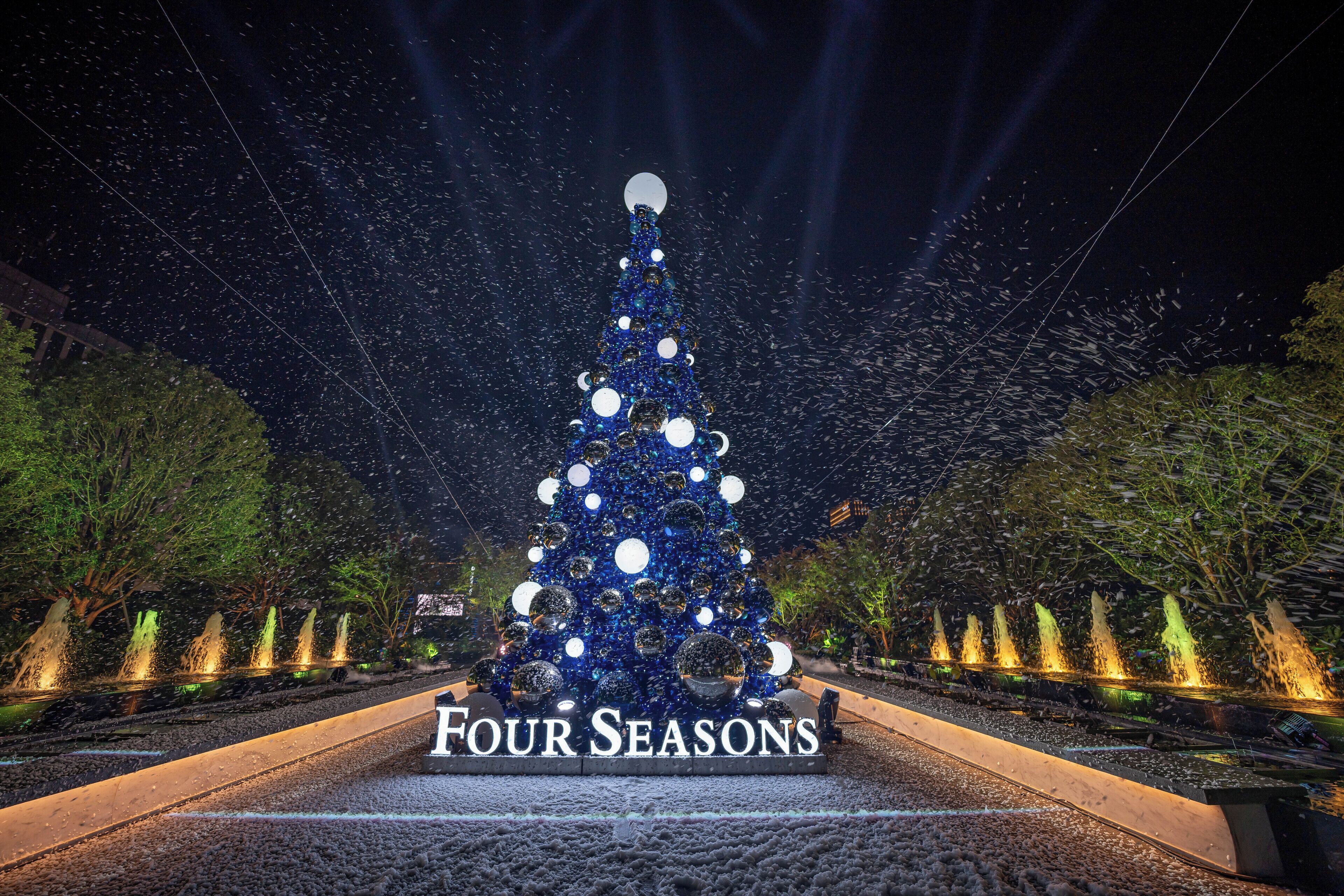 A large, illuminated Christmas tree with the text "FOUR SEASONS" at its base.