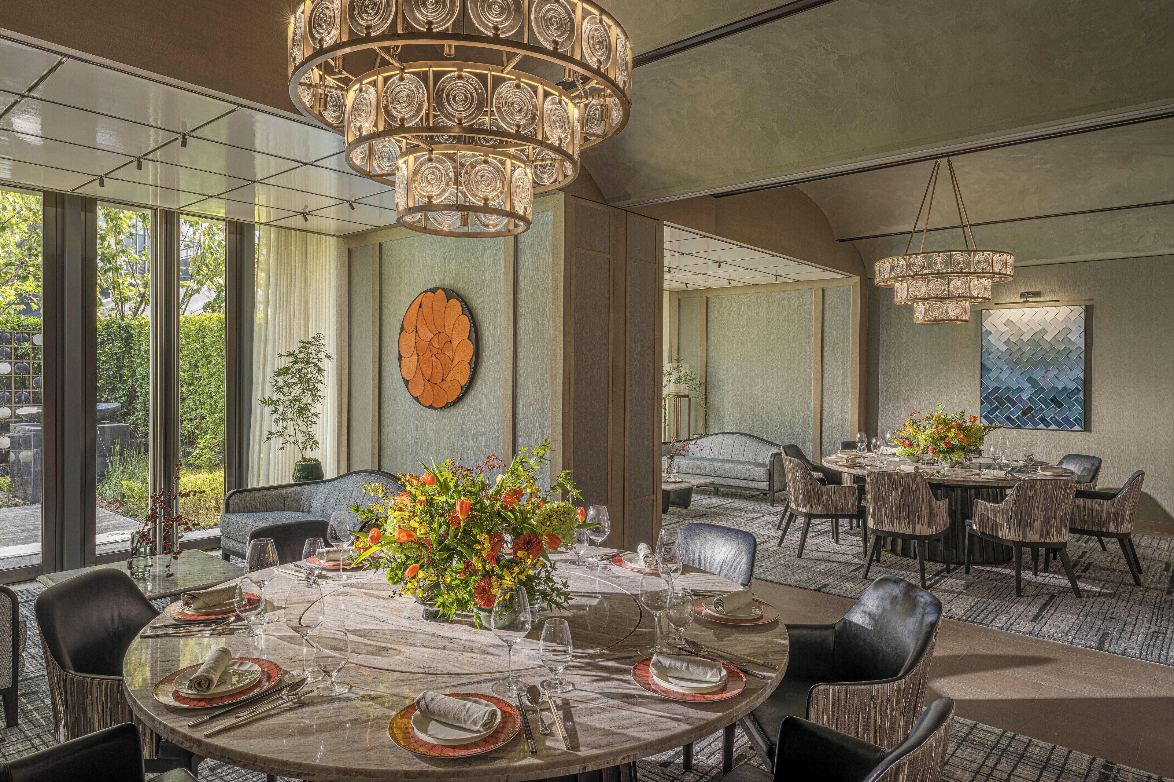 A dining area with a round table set for six, surrounded by wicker chairs.