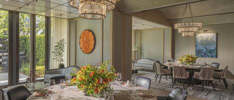 A dining area with a round table set for six, surrounded by wicker chairs.