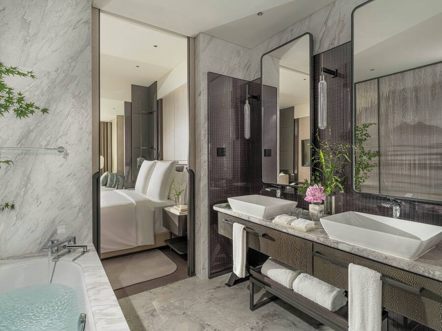 A modern bathroom with a large bathtub, two sinks, and a walk-in shower.
