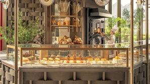 Une vitrine de boulangerie présentant diverses pâtisseries et un chef en uniforme.