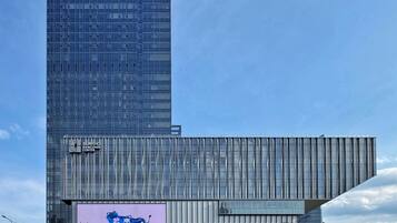 Un bâtiment moderne doté d’une façade en verre et d’une enseigne indiquant « FOUR SEASONS » et « HANGZHOU CENTER ».