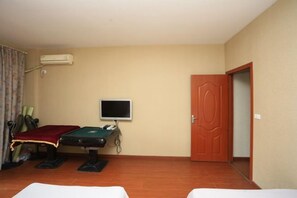 Een kamer met een bed, een massagetafel, een televisie en een deur.