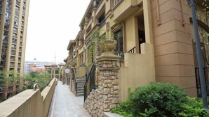 A residential building with a stone facade, multiple balconies, and a narrow pathway leading to the entrance. - Xiaowo Hostel (Chongqing)