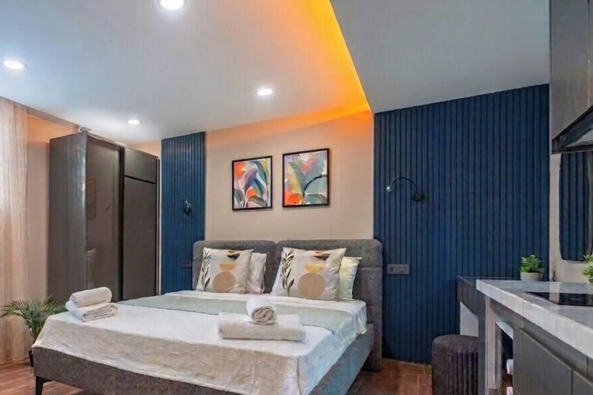 A modern hotel room with a bed, a desk, a chair, and a large window with curtains.