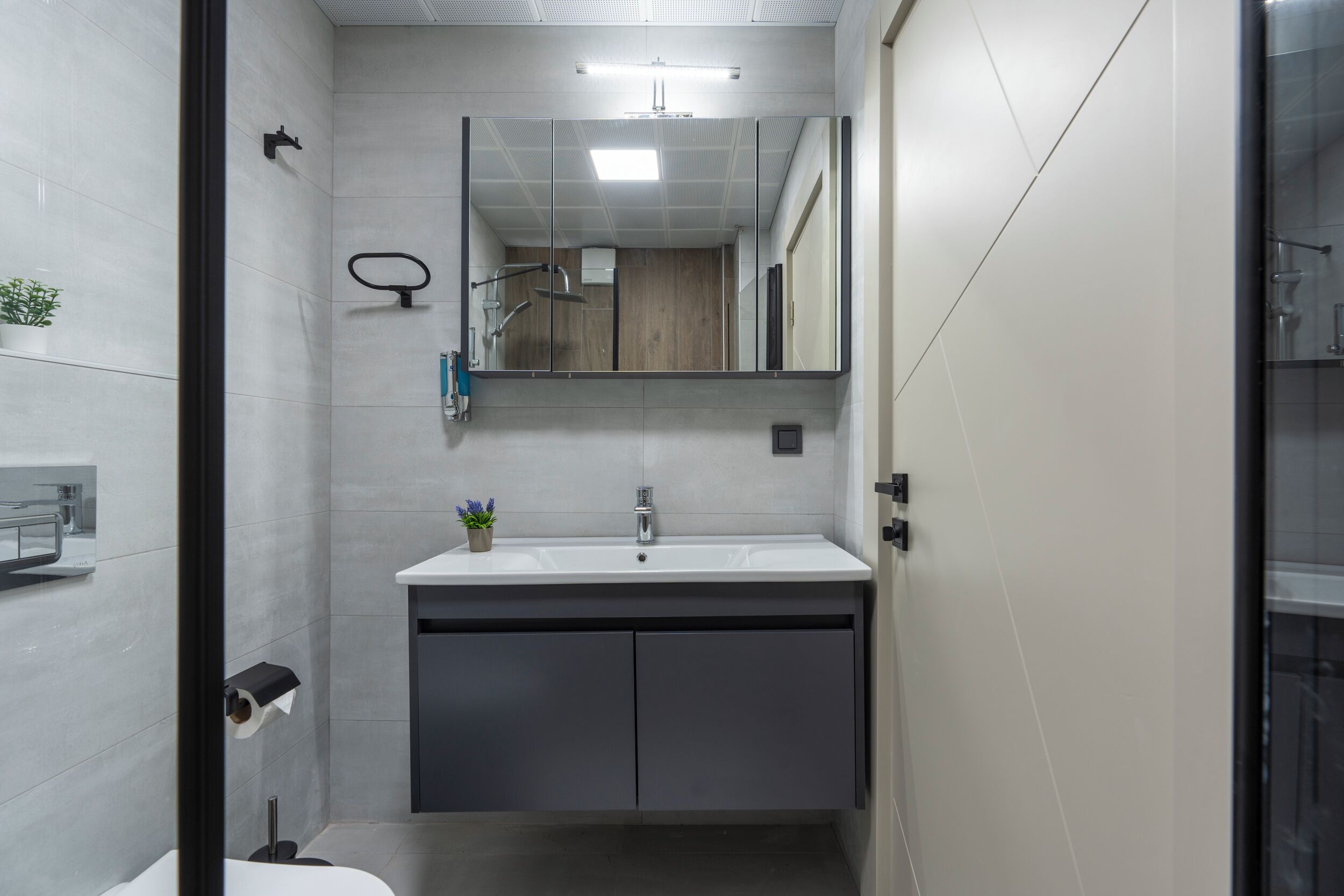 Un baño moderno con lavamanos blanco, espejo y zona de ducha.