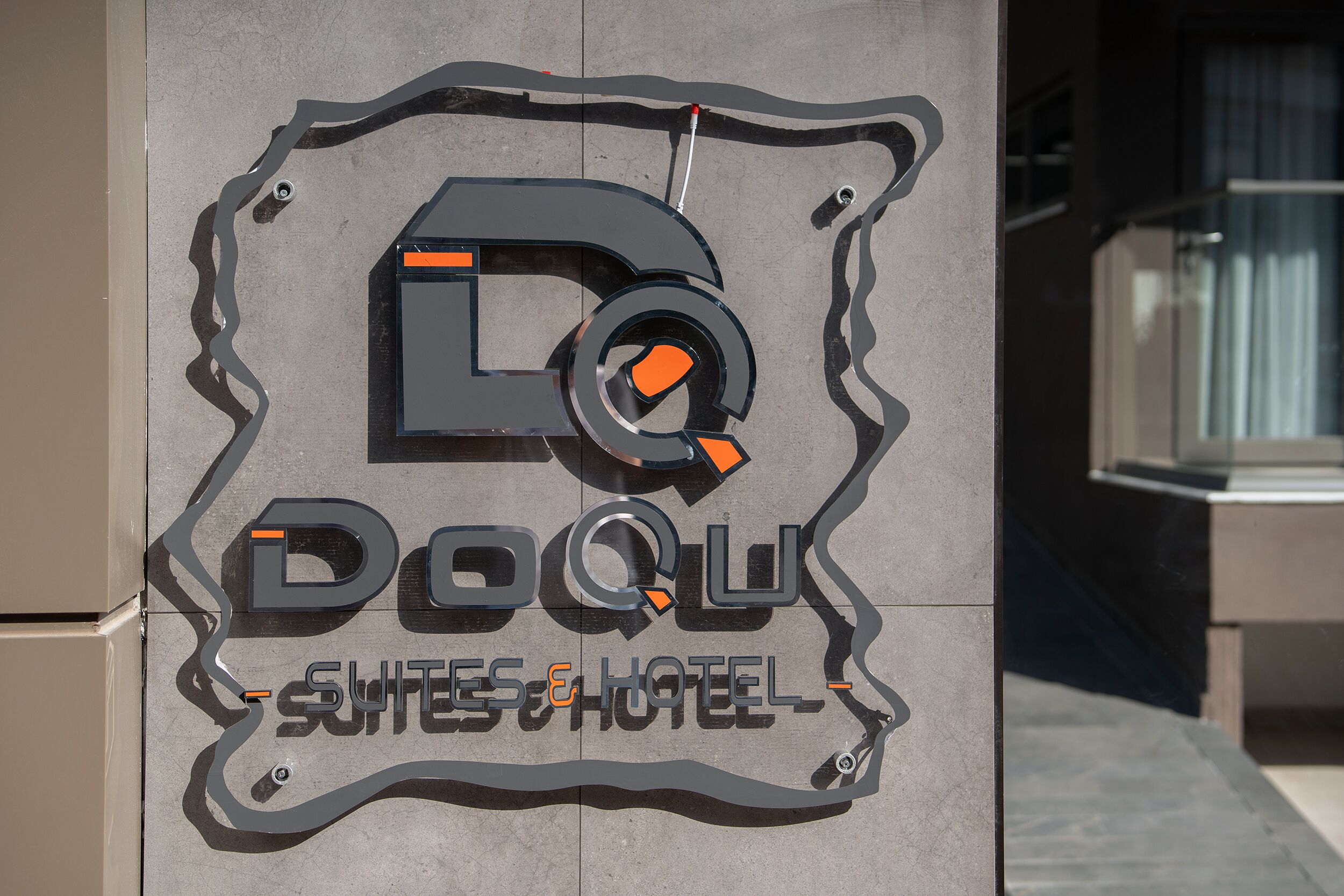 Een bordje voor Doql Suites & Hotel, met een gestileerd logo en de naam van de accommodatie.