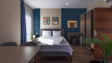Une chambre d’hôtel moderne équipée d’un lit, d’un bureau, d’une chaise, d’une plante en pot et d’un miroir.