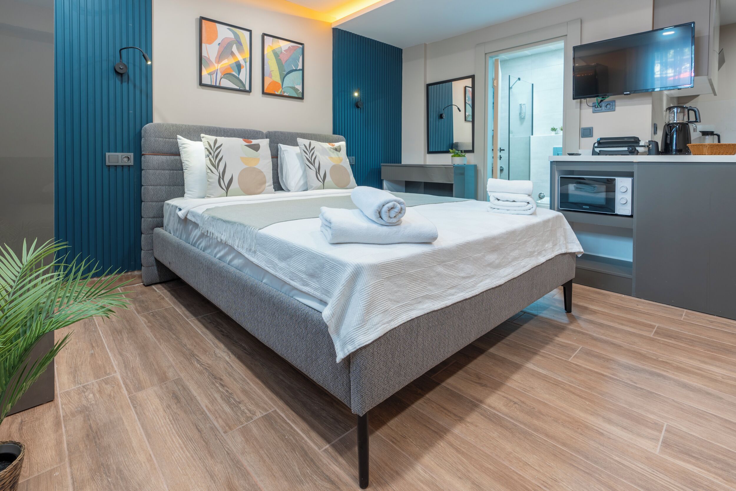 Una habitación de hotel moderna con cama, kitchenette, televisor y baño.