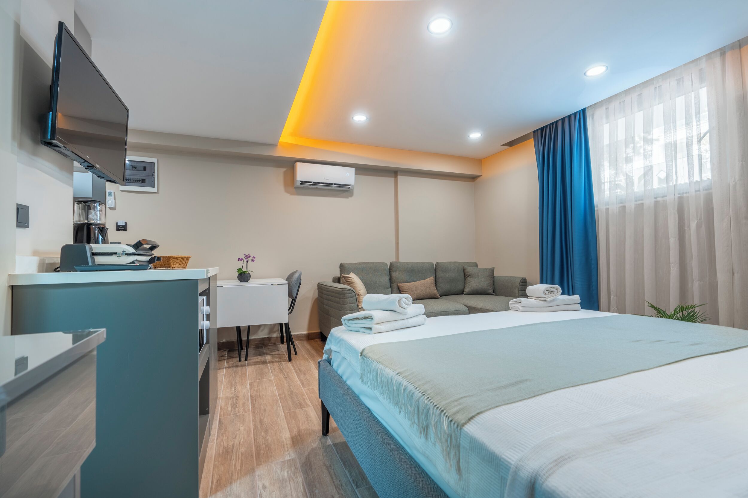A hotel room with a bed, a desk, a sofa, and a TV.