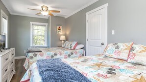 A bedroom with two beds, a ceiling fan, a window, a dresser, and a lamp. - Pelican's Nest - Soundside, 5 min to beach, 2BR 1BA, Atlantic Beach (Atlantic Beach)
