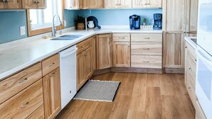A modern kitchen with wooden cabinets, a dishwasher, a coffee maker, and a sink. - Beautiful cozy country home located on 12 acres in a great farming community. (Hancock)