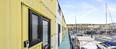 A yellow building with a balcony overlooking a marina with boats.
