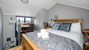 A bedroom with a bed, a desk, and a window.