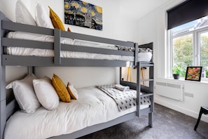 Relax in comfort with a view of the outdoors from this cozy room featuring a bunk bed and large window.