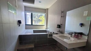 A modern bathroom with a bathtub, a sink, and a large mirror. - Xiang Ting (Nantou)