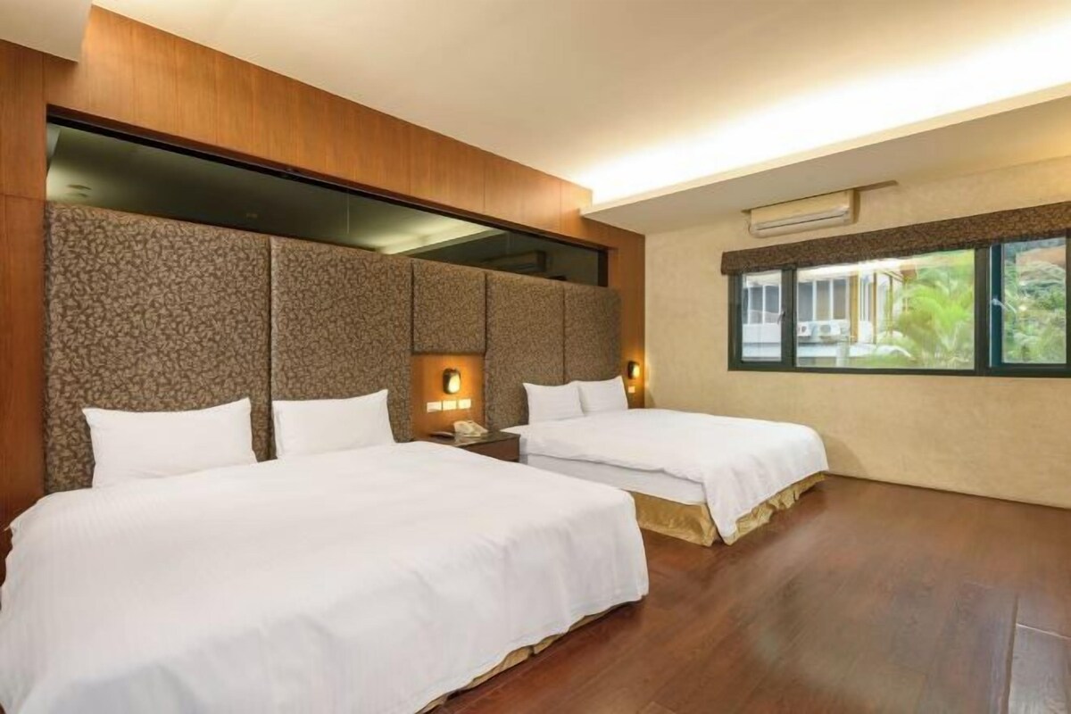 Camera d'albergo con due letti, un'ampia finestra e un arredamento moderno.