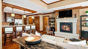 A spacious living area with a fireplace, a kitchen with wooden cabinets, and a bar area.