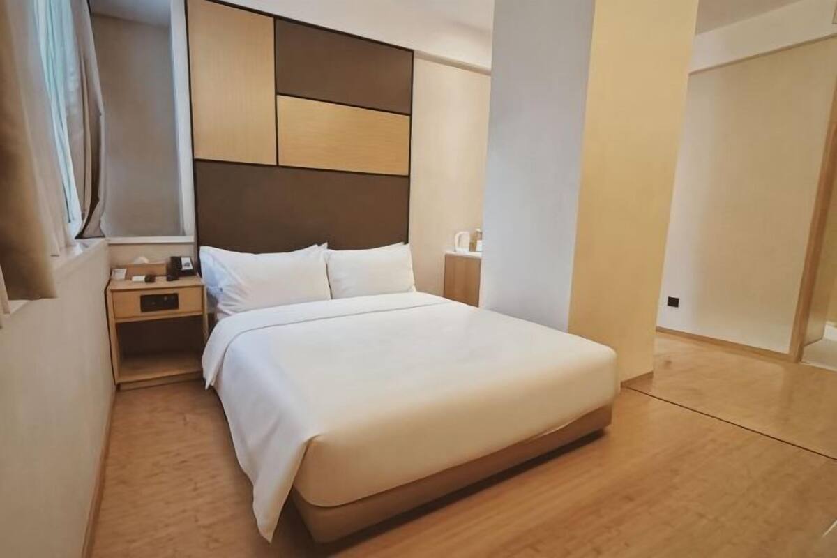 Quarto de hotel moderno com uma cama grande, uma mesinha de cabeceira, um guarda-roupa.