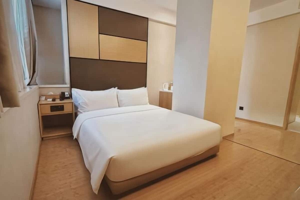 Une chambre dâhĂŽtel moderne avec un grand lit, une table de chevet, une commode et une armoire.
