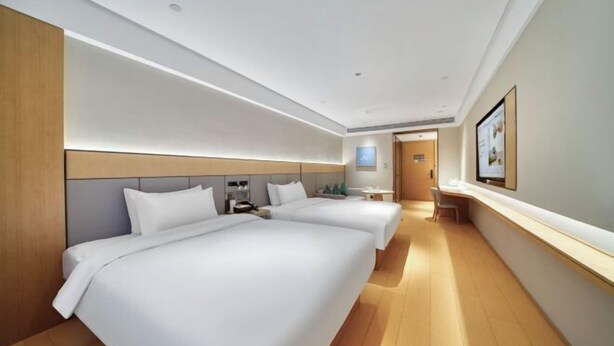 A hotel room with two beds, a wooden headboard, a bedside table with a lamp, and a framed picture on the wall. - Ji Hotel Hangzhou Xiaoshan People Square (Hangzhou)