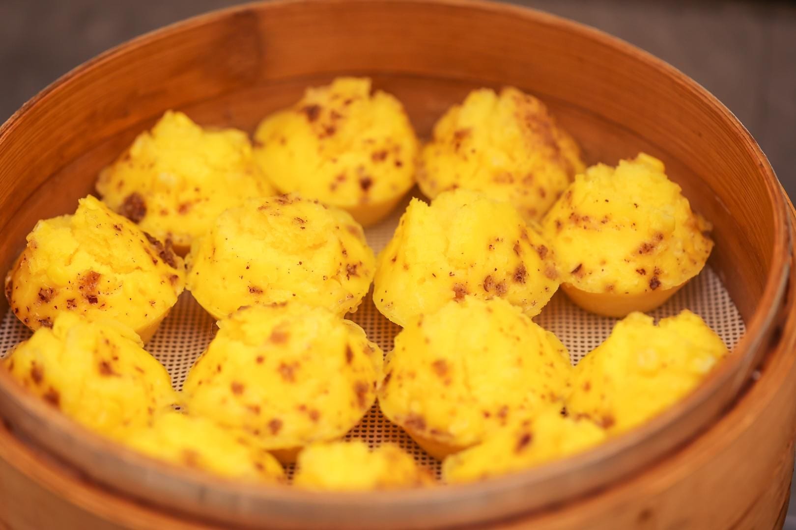 Una vaporera de bambú con albóndigas amarillas.