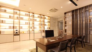 A modern meeting room with a long table, chairs, a flat-screen TV, and illuminated bookshelves. - Ji Hotel Hangzhou Xiaoshan People Square (Hangzhou)