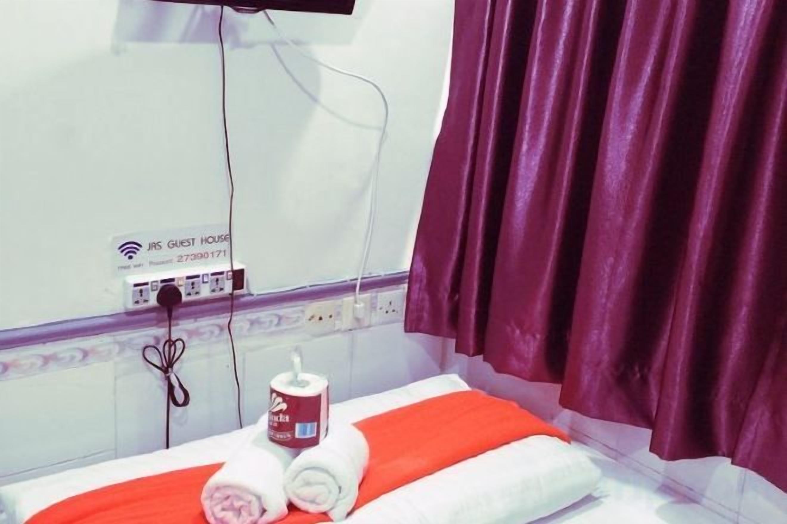 Une chambre d’hôtel équipée d’un lit, d’une prise électrique, d’un téléphone et d’un appareil fixé au mur.