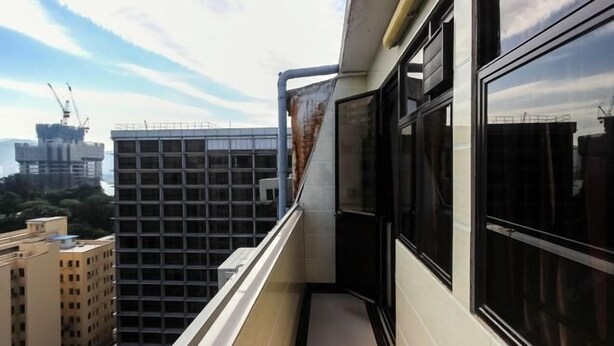 A narrow balcony with a view of surrounding buildings, including a construction site. - Wing Lee Guest House (Hong Kong)