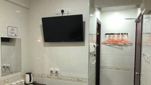 A hotel bathroom with a flat-screen TV, a towel rack, a mirror, and a sink with a dark countertop. - Wing Lee Guest House (Hong Kong)