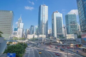 A cityscape with modern high-rise buildings, a multi-lane road, and a pedestrian overpass. - Wing Lee Guest House (Hong Kong)