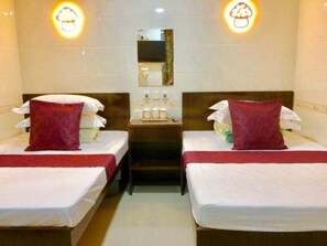 A hotel room with two beds, each with a red pillow, a nightstand with toiletries, and a mirror on the wall. - Wing Lee Guest House (Hong Kong)