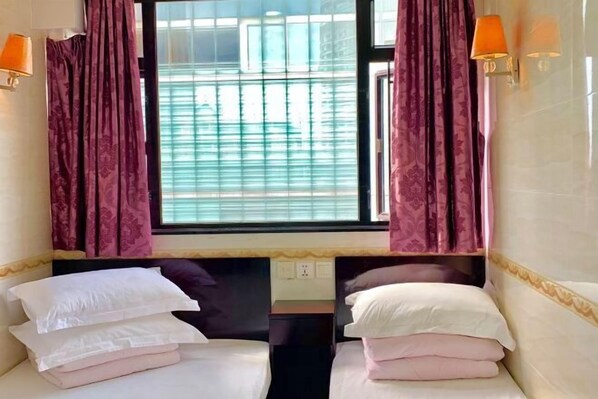 A hotel room with two beds, a window with blinds, and wall-mounted lamps. - Wing Lee Guest House (Hong Kong)