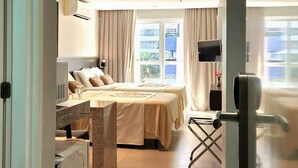 Ein Hotelzimmer mit Bett, Schreibtisch, Fernseher und einem Fenster mit Vorhängen.